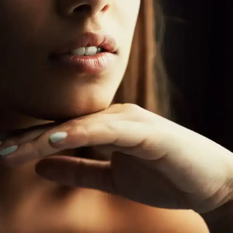 Cropped close-up of a woman’s face resting on her hands, symbolizing the stillness and self-reflection that comes from shadow work and stepping into feminine power.