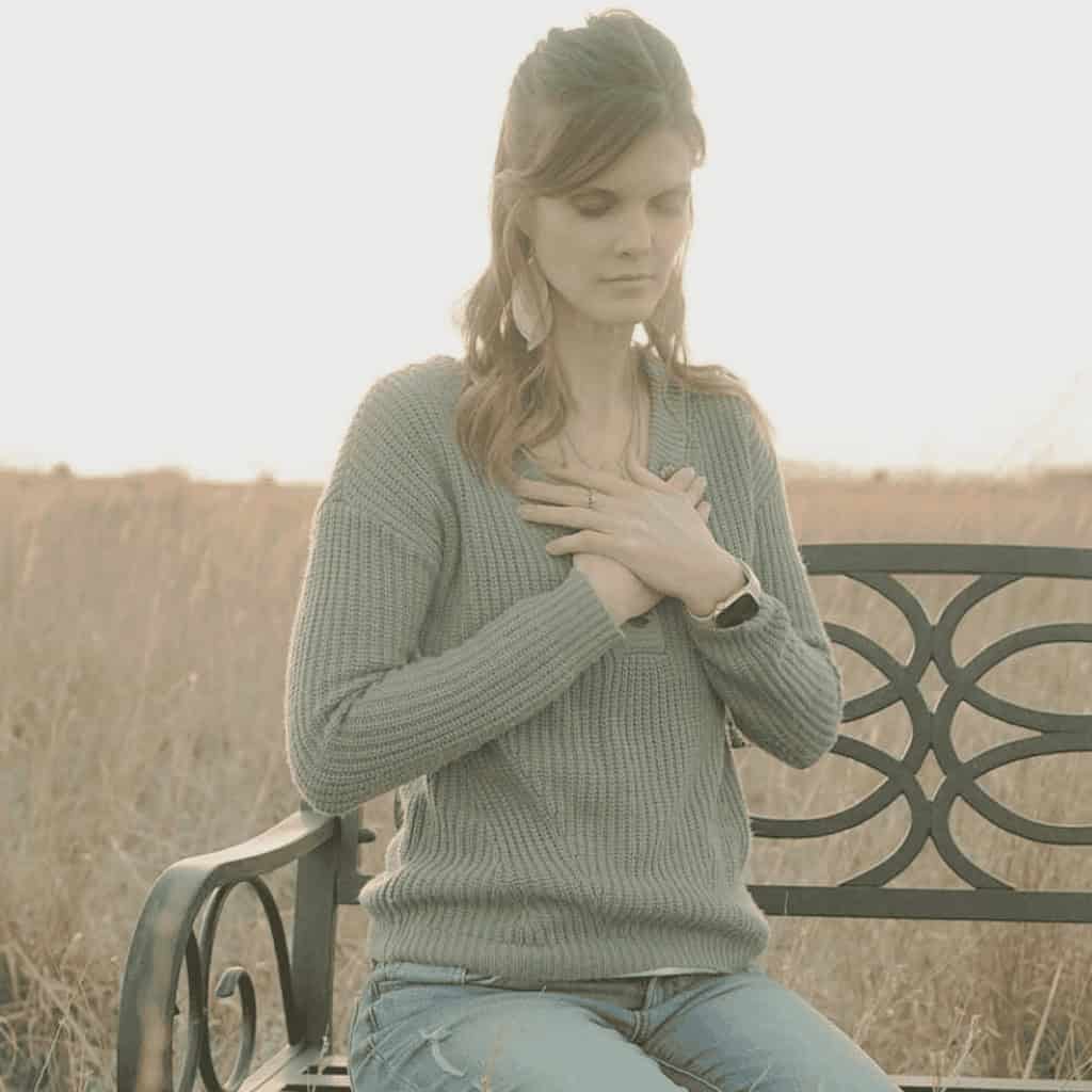 woman holding her chest sitting on chair