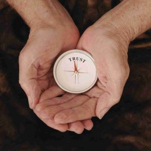 Hands holding a compass labeled trust representing intuition and guidance while learning how to connect to your spirit guide.